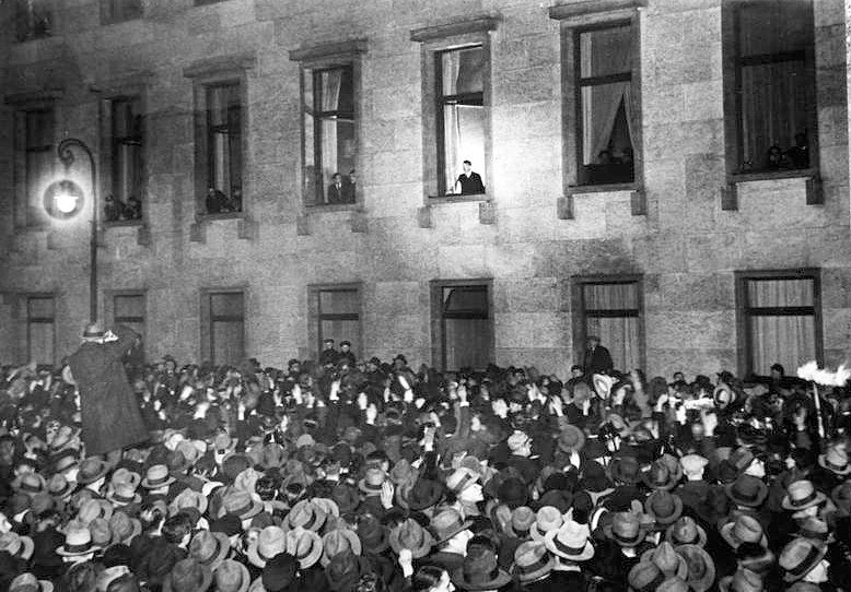 Adolf Hitler zwaait op 30 januari 1933 vanuit het venster van de rijkskanselarij in Berlijn naar een jubelende menigte. De mensen zijn gekomen om zijn benoeming tot rijkskanselier van Duitsland te vieren.