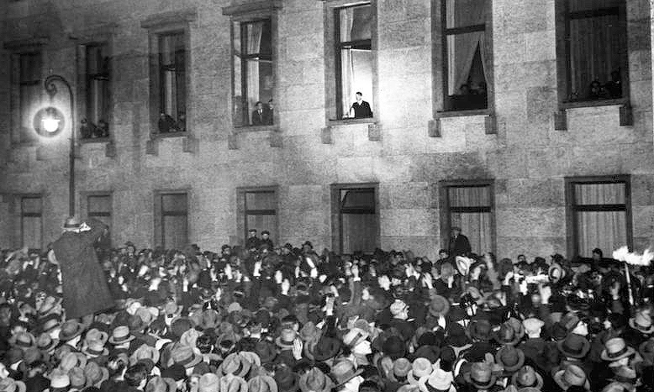 Adolf Hitler waves from the chancellery to the jubilant crowd. They celebrate his appointment as Chancellor of Germany.